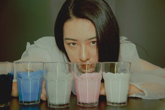 woman sitting at a table with colored glasses on it