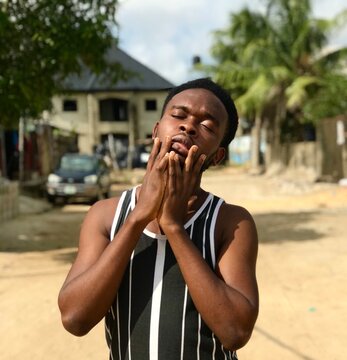 Young African man standing outdoor closing his eyes