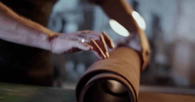 Craftsman unrolling leather on workbench