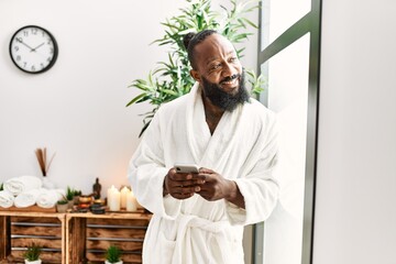 Young african american man smiling confident using smartphone at beauty center