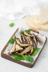 sprats in oil with herbs on a wooden board