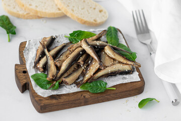 sprats in oil with herbs on a wooden board