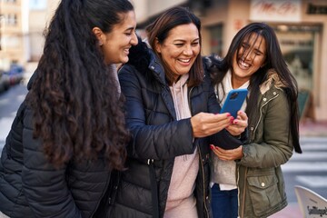 Three woman mother and daughters using smartphone at street