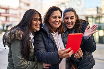 Three woman mother and daughters having video call at street