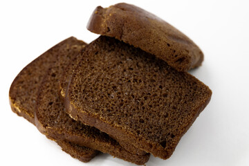 Several sliced ​​pieces of brown rye natural organic bread lie on top of each other on a white background close-up top view