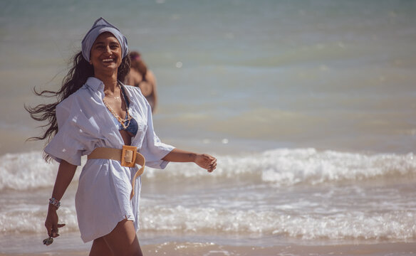 Young woman in blue beach robe and bandana walking on seashore of Valencia, Spain