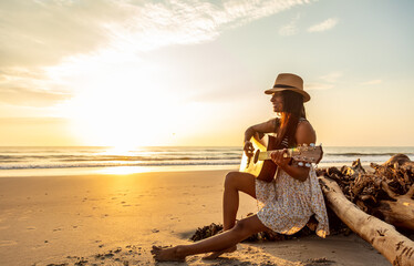 Sunset over ocean with Indian girl playing guitar