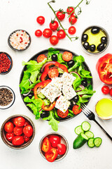 Greek salad with feta cheese, olives, cherry tomato, paprika, cucumber and red onion, healthy vegeterian mediterranean diet food, low calories eating. White stone background, top view