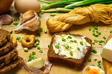 tasty lunch in rural style, healthy food - bread and butter sandwich, feta cheese, eggs, green leek and rye bread, cooked food on a white wooden boards