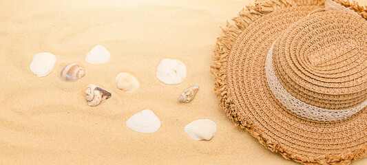 Fototapeta na wymiar Summer background with a hat on the sand and shells