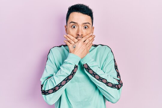 Young hispanic man wearing casual clothes shocked covering mouth with hands for mistake. secret concept.