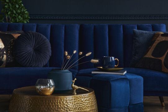 Fototapeta Stylish and elegant details in the glamour living room interior. Golden metal coffee table and creative personal accesories. Dark blue sofa on the background. Template. Copy space..