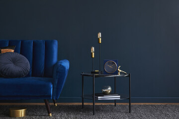 Modern living room interior composition with velvet blue sofa, design side table and elegant home decor. Dark blue wallpaper. Template. Copy space.