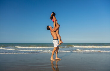 Fototapeta na wymiar Summer fun for ethnic couple playing by ocean