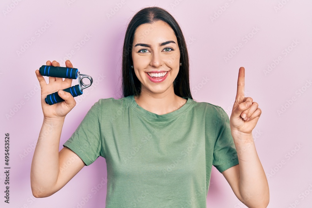 Sticker beautiful woman with blue eyes training muscle with hand grip smiling with an idea or question point