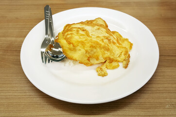 omelet on rice in white dish on wooden table