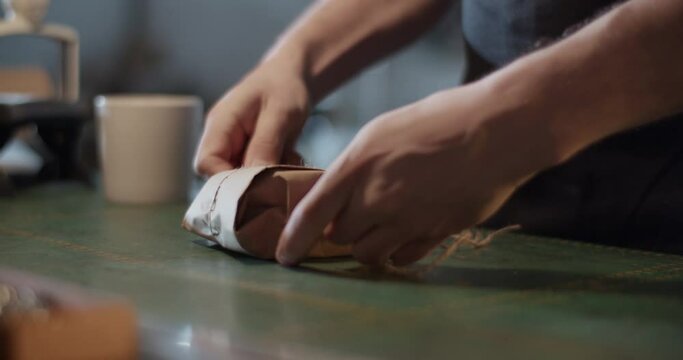 Male artisan wrapping parcel on table