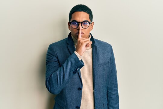 Young handsome hispanic man wearing elegant clothes and glasses asking to be quiet with finger on lips. silence and secret concept.