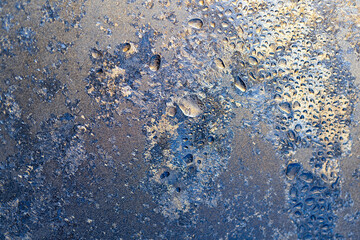 Beautiful texture of ice crystals and frozen water droplets on the glass. Winter silver-blue background