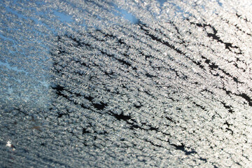 Frost pattern on glass on blue sky background