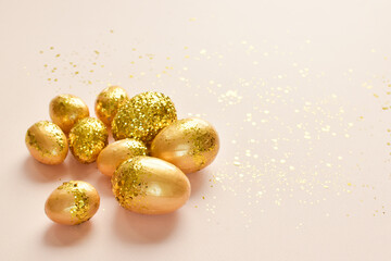 Easter eggs with gold sequins on a beige background.