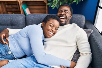 Man and woman couple hugging each other lying on sofa at home