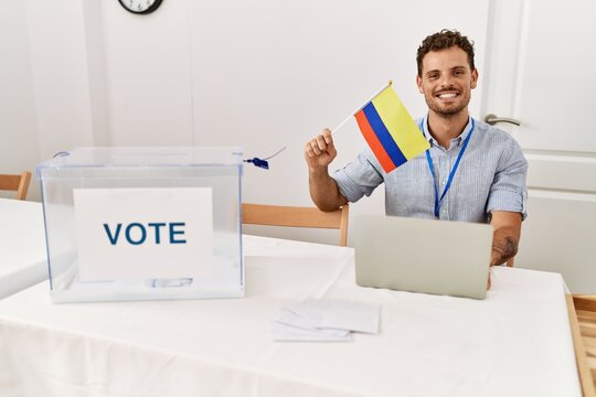 Young hispanic man smiling confident holding colombia flag working at electoral college