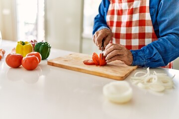 Senior man cutting tomato at kitchen