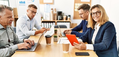 Group of middle age business workers working. Woman smiling happy and looking to the camera at the office.