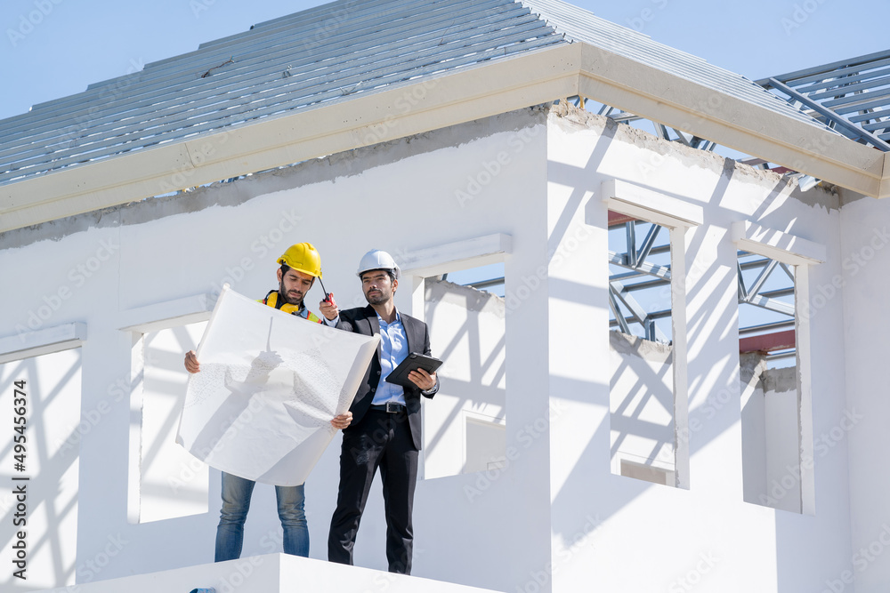 Poster structural engineer and foreman worker with blueprint discuss plan working for the new house constru