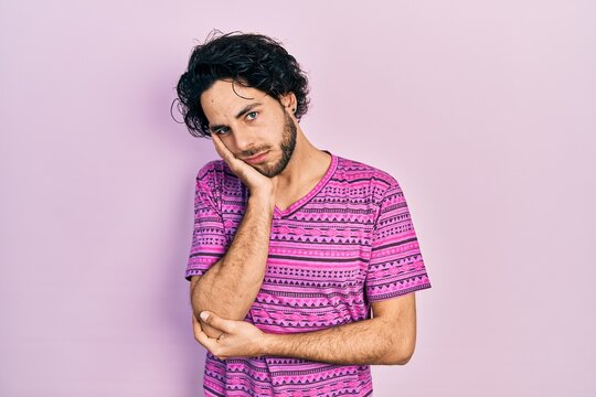 Handsome hispanic man wearing casual pink t shirt thinking looking tired and bored with depression problems with crossed arms.
