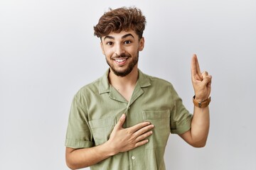 Young arab doctor man standing over isolated background smiling swearing with hand on chest and...