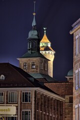Im Vordergrund der Trum des alten Rathauses von Nürnberg und im Hintergrund der Sinwellturm der Kaiserburg Nürnberg, bei Nacht. 
