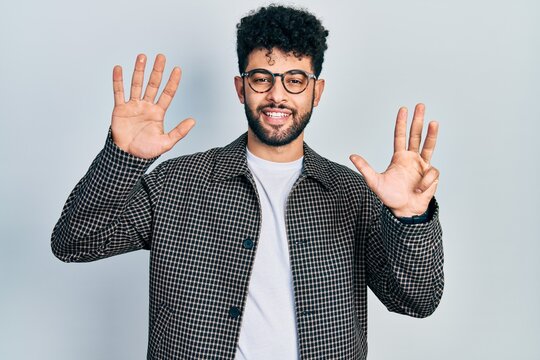 Young arab man with beard wearing glasses showing and pointing up with fingers number nine while smiling confident and happy.
