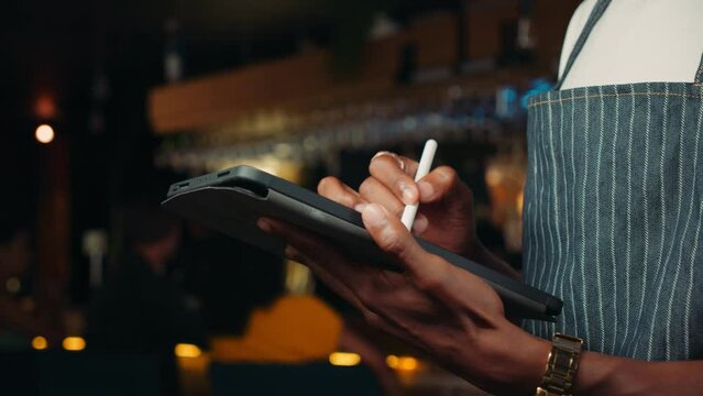 Close up of male waiter swiping on digital tablet in a restuarant