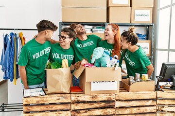 Group of young volunteers smiing happy and hugging standing at charity center.