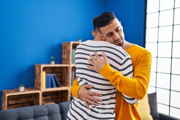 Two man couple hugging each other standing at home