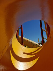 Cilindro de pl&agrave;stico para tobog&agrave;n de juegos infantiles con sombra sobre luz del sol, presenta un bello dise&ntilde;o abstracto de &ograve;valo con fondo de escaleras y cielo azul