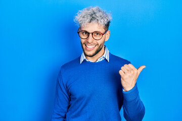 Young hispanic man with modern dyed hair wearing sweater and glasses smiling with happy face...