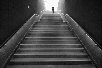 Fototapeta na wymiar Rear view of an unrecognizable man walking up subway stairs into the light
