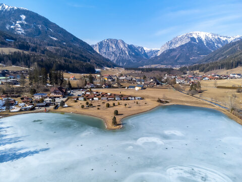 aerial view frozen lake Zenzsee in Styria, Austria.In the background mountain range Hochschwab with peaks Pribitz and Messnerin