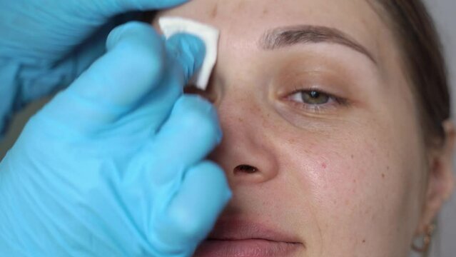 female eyebrows and eyes close-up, the paint is removed from the eyebrows with a damp cotton pad. fresh henna brow