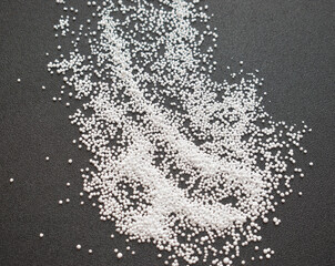 Small round granules on a black background. Laundry bleaching powder in granules.