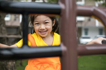 Fototapeta na wymiar Asian happy girl with orange dress is playing in the playground.