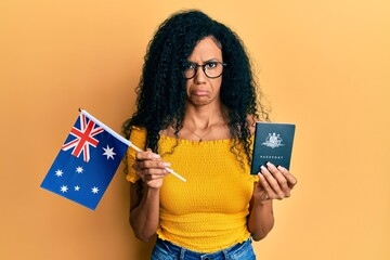 Middle age african american woman holding australian flag and passport depressed and worry for...
