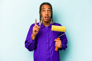 Young African American painter man isolated on blue background pointing upside with opened mouth.