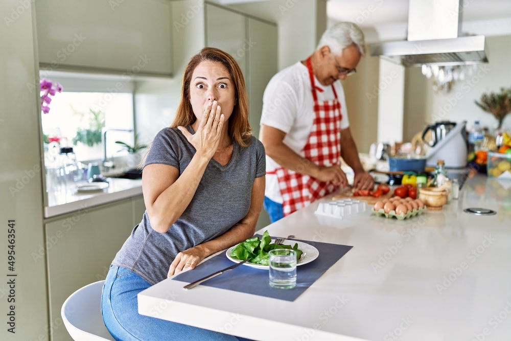 Canvas Prints Middle age hispanic couple eating healthy salad at home covering mouth with hand, shocked and afraid for mistake. surprised expression