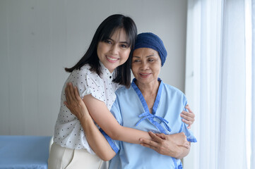 Cancer patient woman wearing head scarf and her supportive daughter in hospital, health and insurance concept.