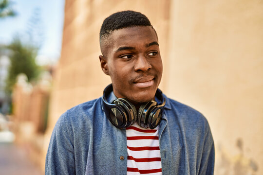 Young african american man with relaxed expression using headphones at the city.