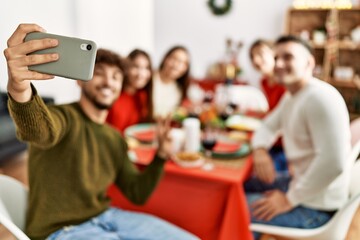 Group of young people having christmas dinner make selfie by the smartphone at home.